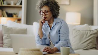 Femme réfléchissant tout en utilisant un ordinateur portable