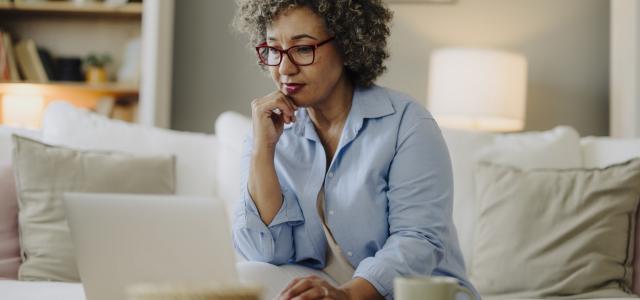 Femme réfléchissant tout en utilisant un ordinateur portable